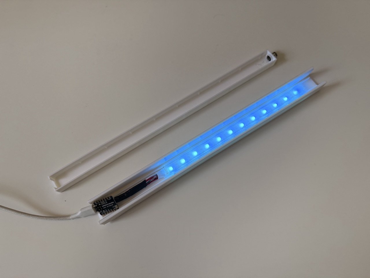 3D-printed LED light bar wall-mounted, glowing teal